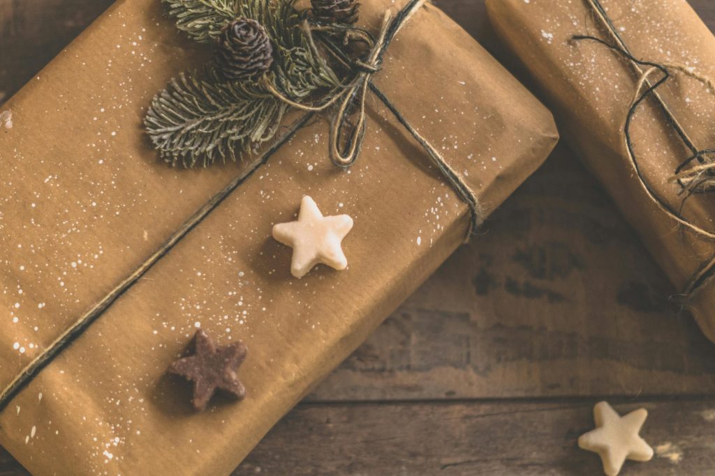 Cozy rustic Christmas presents wrapped in brown paper with star decorations and pine accents.